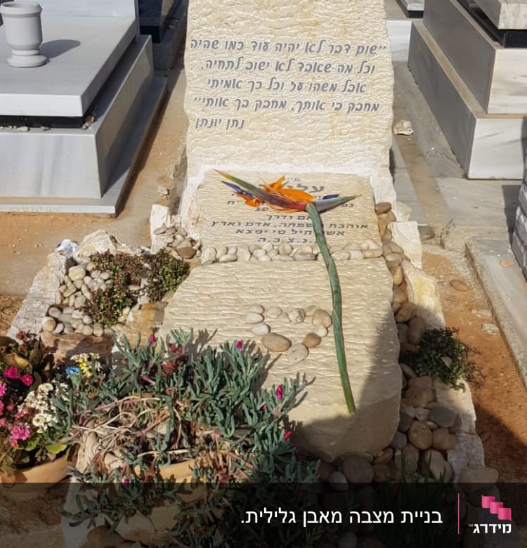 מצבות עם כיתוב בעברית ופרחים על הקבר